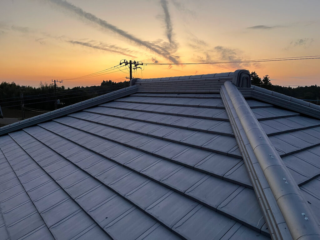 夕焼け空を背景に、美しく仕上がった瓦屋根の全景。丁寧に施工された棟部分が特徴的。